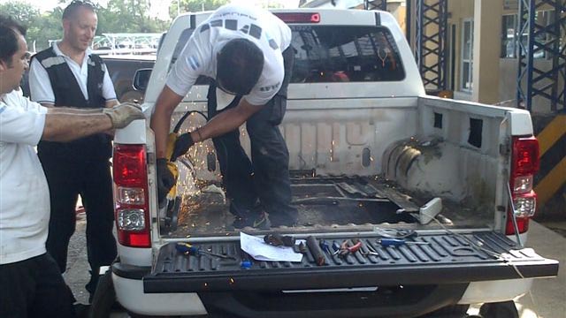Personal de Aduanas trabaja para "descubir" la droga camuflada en la camioneta.
