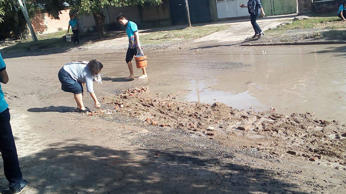 Alumnos secundarios rellenan un bache en el barrio Lote Cuatro
