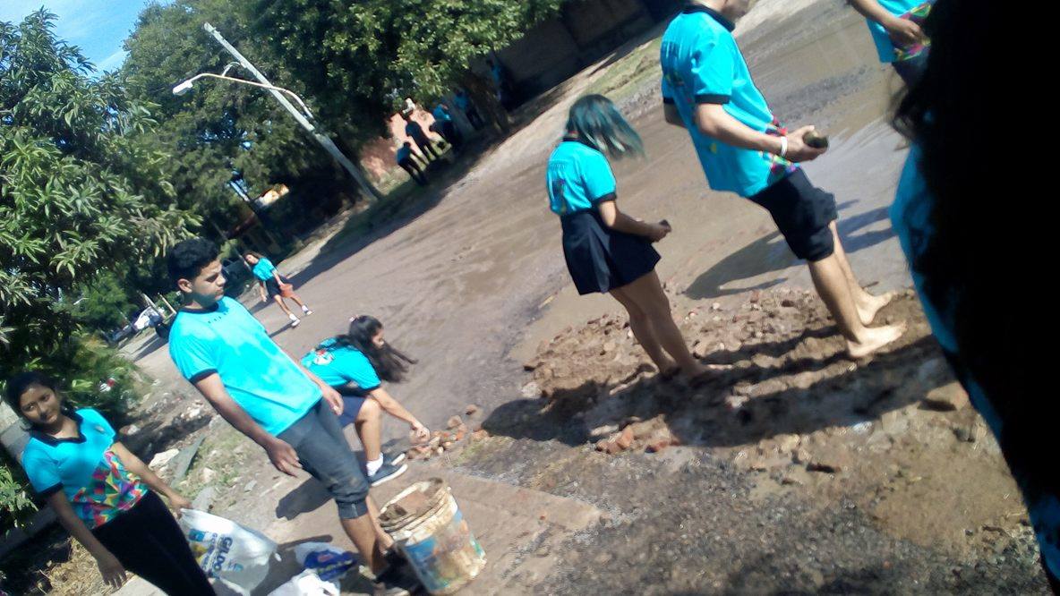 Alumnos secundarios rellenan un bache en el barrio Lote Cuatro