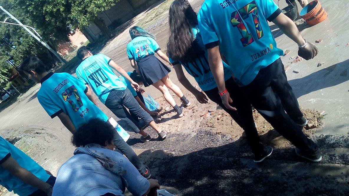 Alumnos secundarios rellenan un bache en el barrio Lote Cuatro