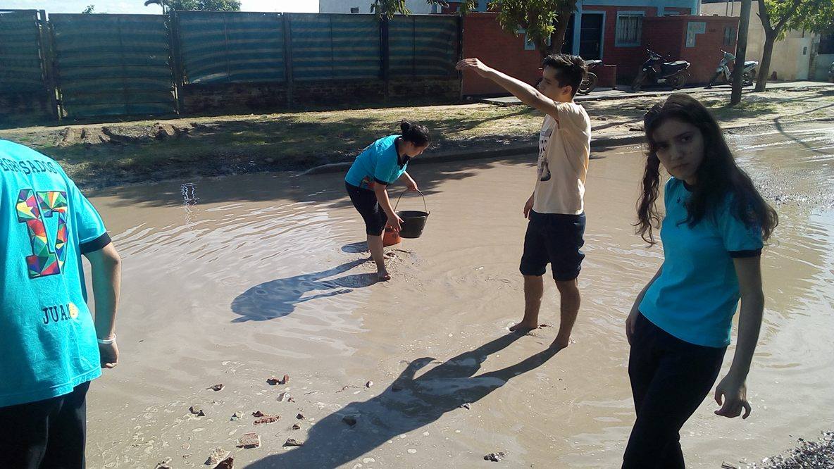 Alumnos secundarios rellenan un bache en el barrio Lote Cuatro