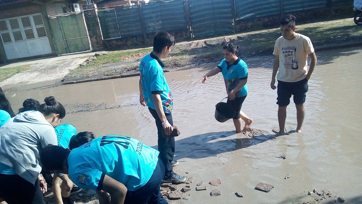 Alumnos secundarios rellenan un bache en el barrio Lote Cuatro